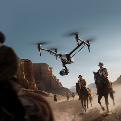 DJI Inspire 3 drone in action flying over a scenic desert landscape, capturing aerial footage of horseback riders.